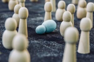 a blue wooden chess piece lies on its side amidst similar pieces that are standing up and a different colour