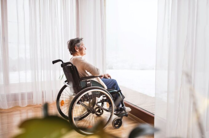 A women in a wheelchair looks out a floor to ceiling window, illustrative of consider mobility as a key lifestyle planning factor.