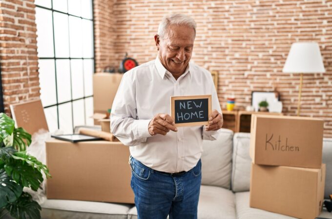 senior-man-smiling-confident-holding-blackboard-new-home