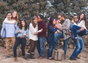 5 or 6 couples in their 30s and 40s posing for a photo in the forest