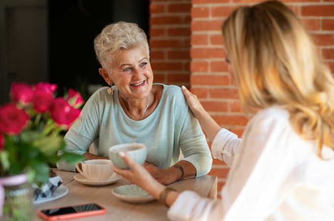 Adult daughter and her mother drinking tea and chatting